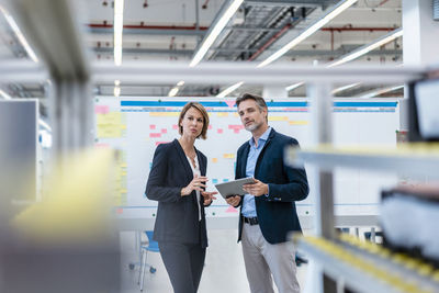 Businessman and businesswoman talking in a factory hall