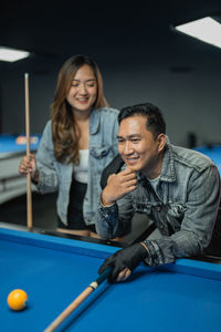 Portrait of smiling friends playing pool