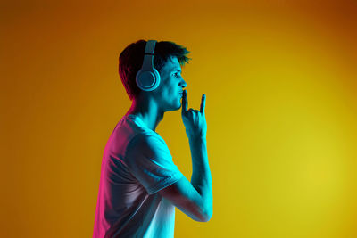 Rear view of woman standing against yellow background