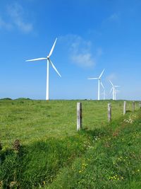 Windmills on field against clear sky