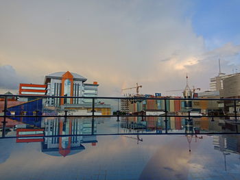 Buildings by sea against sky during sunset