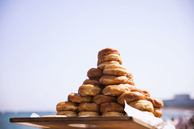 Stacked donuts in tray against clear sky
