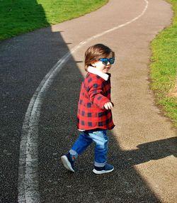 Boy walking on road during sunny day