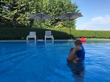 Father carrying son on shoulders in swimming pool