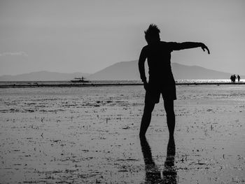 Silhouette man standing on beach against sky