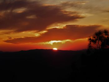 Scenic view of silhouette landscape against dramatic sky during sunset
