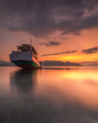 Fishing boat in sea against sky during sunset