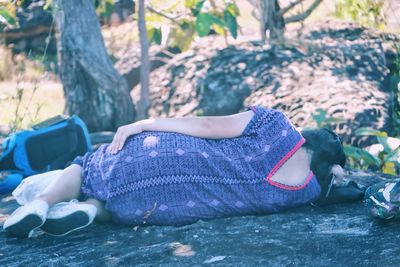 Woman sleeping on rock in forest