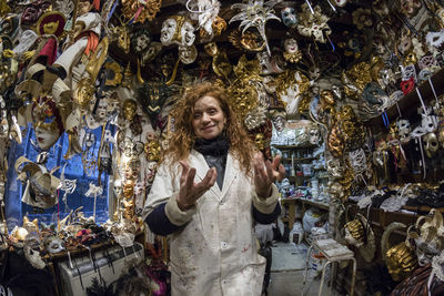 Portrait of woman smiling while standing amidst masks in store