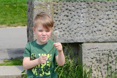 A happy boy blows on a bouquet of white dandelions