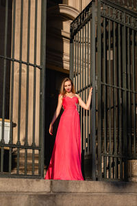 Low angle view of beautiful woman in pink evening gown standing at doorway