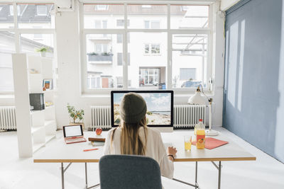 Rear view of woman sitting on table at home