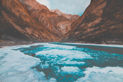 Frozen stream by rocky mountains