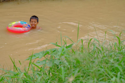 Portrait of smiling boy with inflatable ring in lake