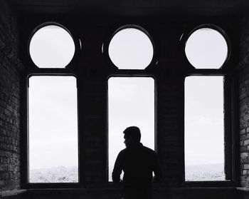 Rear view of man standing by window