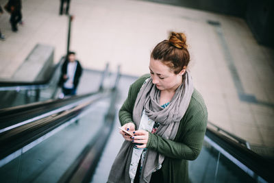 Woman looking at camera while standing on escalator