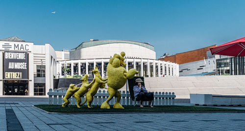 Statue in city against clear blue sky