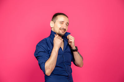 Portrait of a smiling young man against pink background