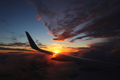 Close-up of airplane wing against sky during sunset