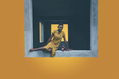 Portrait of woman sitting on window