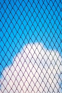 Low angle view of chainlink fence against blue sky