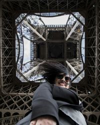 Directly below shot of woman standing under eiffel tower