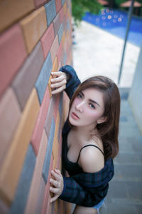 Portrait of young woman standing against wall