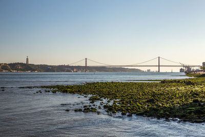 Suspension bridge over river against sky