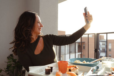 Young woman using mobile phone while sitting on table