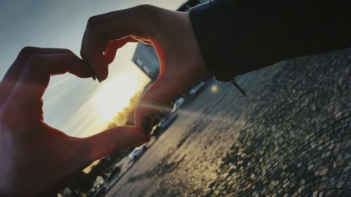 Close-up of hand holding sun against sky during sunset