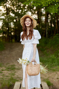 Portrait of young woman standing against plants