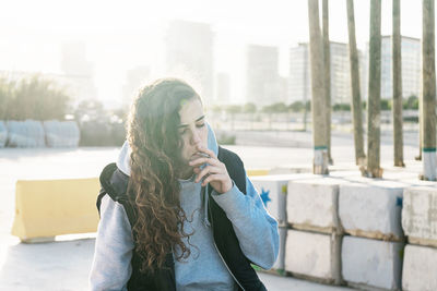 Teenage girl smoking cigarette while sitting outdoors