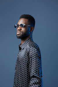 Young man standing against blue background
