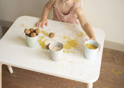 Toddler girl playing with grain, nuts, pasta and rice sitting at table.sensorial early development