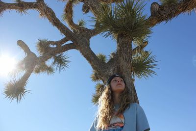 Low angle portrait of young woman against sky