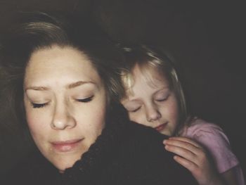 Close-up of mother and daughter sleeping on bed