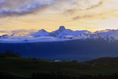 Scenic view of snowcapped mountains against sky during sunset