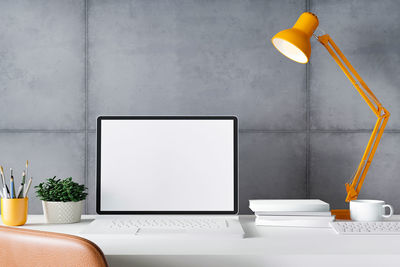 Electric lamp on table against white wall