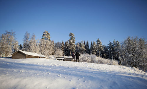 Low angle view of people standing on snow covered hill by trees during winter