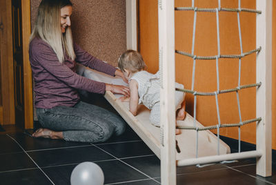 Active games for baby indoors activities. toddler girl play with mom on home wooden playsets. 