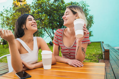 Smiling lesbians enjoying coffee on table