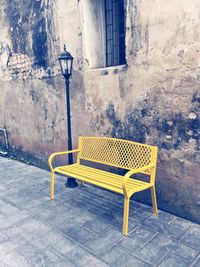 Empty bench on street against building