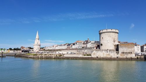 Buildings at waterfront against blue sky