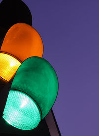 Low angle view of illuminated road signal against blue sky