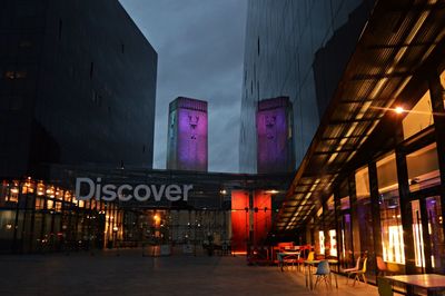 Illuminated street amidst buildings in city at night