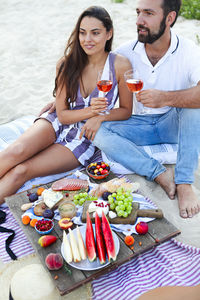 Young couple sitting on beach while having food