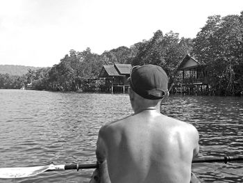 Rear view of shirtless man looking at lake against sky