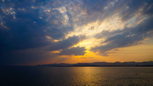 Scenic view of sea against dramatic sky during sunset