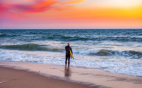 Full length of surfer standing on sand at beach