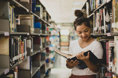 Young woman using mobile phone in library